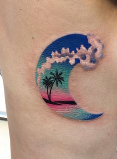 a woman's stomach with a palm tree and wave tattoo on her side belly