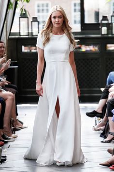 a woman in a white dress walking down the runway