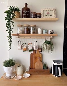 a kitchen counter with coffee cups and mugs on the shelf above it is a wooden cutting board