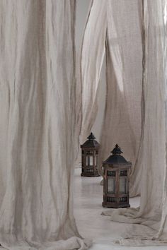 three lanterns are sitting in front of sheer curtained walls and drapes on the floor