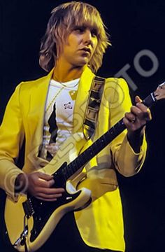 a man in a yellow suit playing an electric guitar