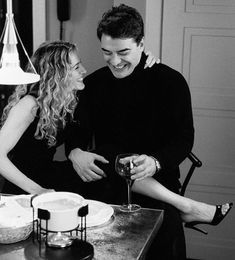 a man and woman standing next to each other at a table with cake on it