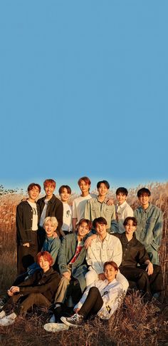 a group of young men posing for a photo in front of some tall grass and blue sky