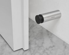 a close up of a door handle on a white door with marble flooring and walls