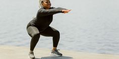 a woman is doing yoga outside by the water