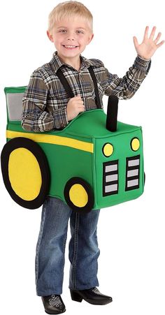 a young boy wearing a green and yellow tractor costume with his hands in the air