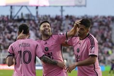 three soccer players are congratulating each other on the field in front of an audience