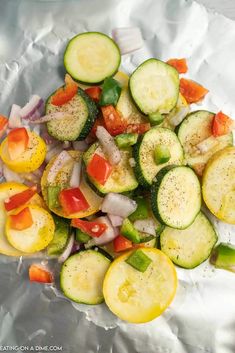 sliced cucumbers, onions, and peppers on aluminum foil with seasoning sprinkles