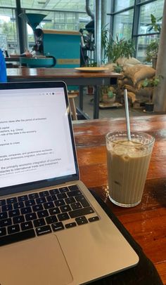 an open laptop computer sitting on top of a wooden table next to a cup of coffee