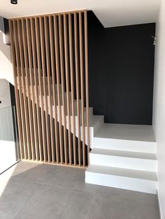 an empty room with white stairs and wooden slats on the wall next to it