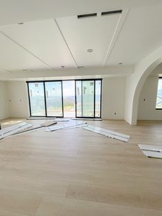 an empty room with wood floors and large windows