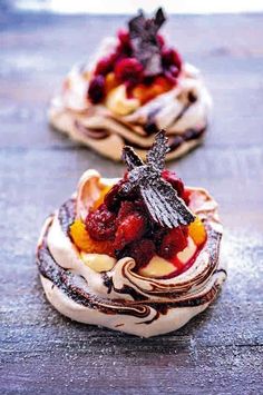 three desserts with fruit on top are sitting on the table