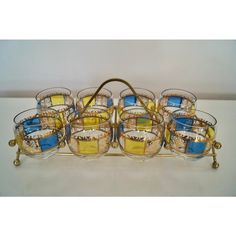 a set of twelve glass dishes with gold rims on a metal stand, in the shape of a basket