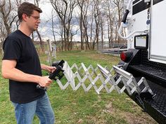 a man standing in front of a truck holding a remote control device to the back of it