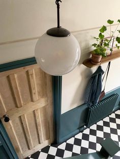 a room with black and white checkered flooring, green door and light fixture