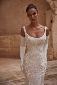 a woman in a white wedding dress with long sleeves and an off the shoulder top