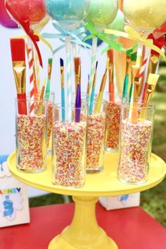 there are many glasses with confetti in them on the cake stand at this birthday party