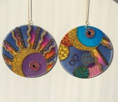 two circular pendants hanging from chains on a white wall, each with different designs and colors