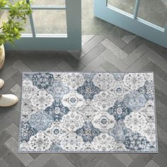 a blue and white area rug on the floor next to a potted plant in front of a window