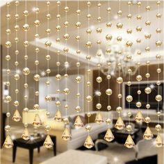 a living room filled with furniture and lots of hanging glass beads on the ceiling above it