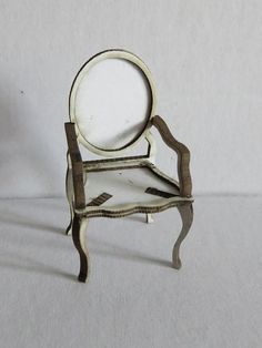 a miniature chair with a magnifying glass on it's back end, sitting in front of a white background