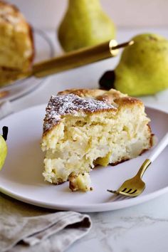 a piece of cake sitting on top of a white plate next to two pears