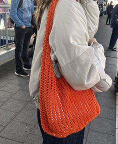 a woman with an orange crocheted bag on her back