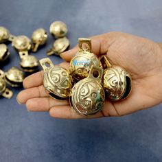 a person is holding some gold bells in their hand