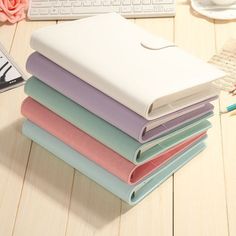 a stack of notebooks sitting on top of a wooden table next to a keyboard