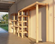 an empty room with wooden shelves on the wall and open doors leading to another area