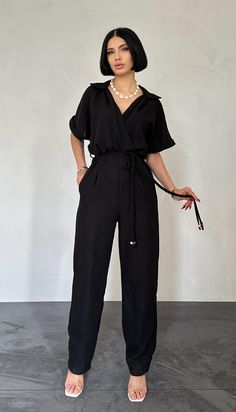 The product on the model is size S/36. Black Relaxed Fit Jumpsuit For Workwear, Casual V-neck Pantsuit For Work, Casual V-neck Pantsuit For Night Out, Summer Black Workwear Pantsuit, Black Summer Workwear Pantsuit, Chic Short Sleeve Workwear Pantsuit, Chic Short Sleeve Pantsuit For Work, Trendy Black Jumpsuits And Rompers For Work, Chic Relaxed Fit Jumpsuits For Workwear