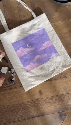 someone is making a paper bag with clouds and a moon in the sky on it