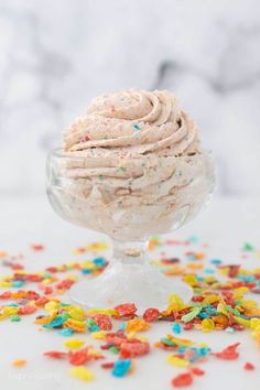 an ice cream sundae with sprinkles in a glass bowl on a table