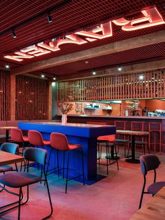 an empty restaurant with blue counter tops and red chairs around the bar, along with neon lights on the ceiling