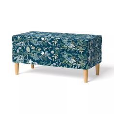 an upholstered footstool with blue and green floral print on the cover