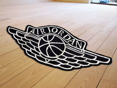 an air jordan basketball logo is on the floor in front of a window with wood floors