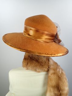 This butterscotch/camel/caramel widebrim hat is flat out fabulous! It is hand blocked over a vintage hat block and hand sewn with many tiny stitches. The crown (top) of the hat comes to a soft point and the brim has a slight down turn. Millinery wire is sewed inside of the brim edge to help the hat keep it's shape. The band and brim edge is a gorgeous hand dyed silk ribbon. It's finished with a three loop now, a pretty silk and velvet flower and a large bow of vintage netting. An inner adjustabl Vintage Fitted Felt Hat For Fall, Vintage Fur Felt Fedora For Fall, Vintage Style Fitted Beige Fedora, Vintage Fitted Beige Fedora, Fitted Vintage Beige Fedora, Fitted Beige Vintage Fedora, Elegant Brown Wool Top Hat, Elegant Brown Cloche Hat With Curved Brim, Vintage Wide Brim Fur Felt Fedora