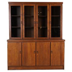 a wooden cabinet with glass doors on the top and bottom shelves, against a white background