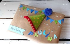 a birthday present wrapped in brown paper with a green tree on it and blue pom - poms