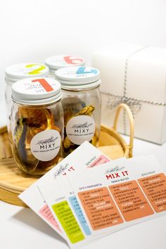 jars filled with different types of pickles next to a gift tag and paper on a tray