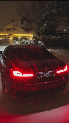 a red car parked in the snow at night with its lights on and it's headlights turned on