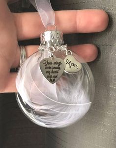 a person holding a glass ornament with two hearts on it and the words you're always my heart