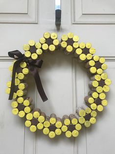 a wreath made out of wine corks is hanging on the door with a ribbon