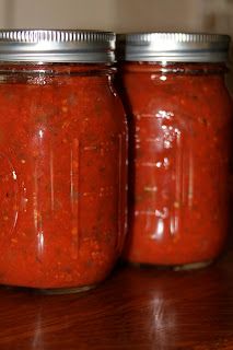 three jars filled with red sauce sitting on top of a wooden table