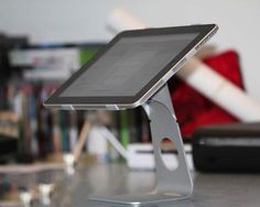 an electronic device sitting on top of a table next to a remote control and bookshelf