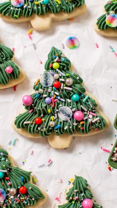 decorated cookies with green icing and sprinkles are on a white surface