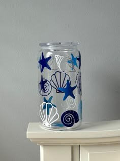 a glass jar sitting on top of a white dresser next to a wall with blue stars and seashells painted on it