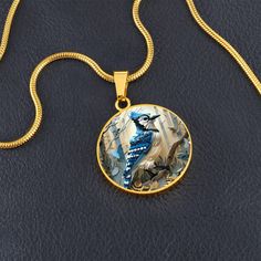 Introducing our exquisite Circle Pendant Necklace, featuring the vibrant blue jay perched gracefully amidst an enchanting woodland. This design captures the blue jay's striking plumage with a mosaic of delicate shades of blue and white, set against a background of softly illuminated trees. Forged from premium surgical steel and available with a lavish 18k gold finish, this innovative jewelry boasts our exclusive design, handcrafted with care right here in the U.S.A by our dedicated team of skilled working mothers. When you choose our necklace, you not only acquire a stunning memento for yourself or a cherished one but also champion the empowerment of working mothers and vibrant communities. Rest assured, your satisfaction is paramount to us, backed by our 100% Happiness Guarantee, ensuring Blue Nature-inspired Round Pendant Necklace, Illuminated Trees, Circle Pendant Necklace, Luxury Necklace, White Set, Blue Jay, Vibrant Blue, Working Moms, Circle Pendant