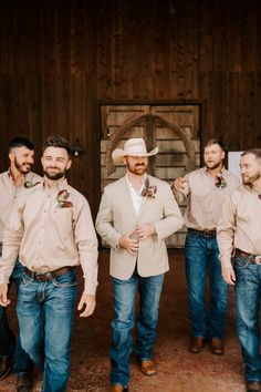 a group of men standing next to each other in front of a wooden wall and door