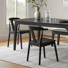 a dining room table with two chairs and a vase